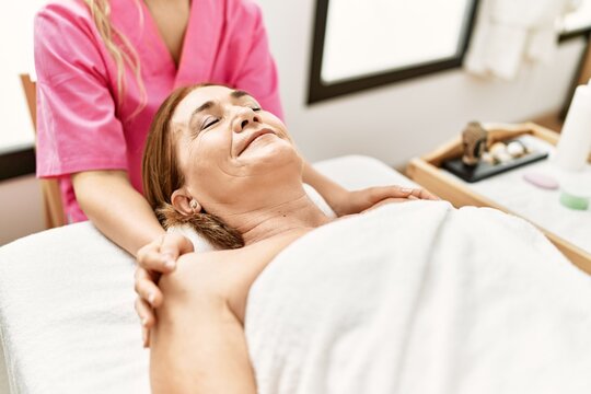 Middle age caucasian woman having shoulders massage at beauty center