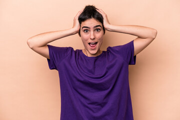 Young caucasian woman isolated on beige background screaming, very excited, passionate, satisfied with something.