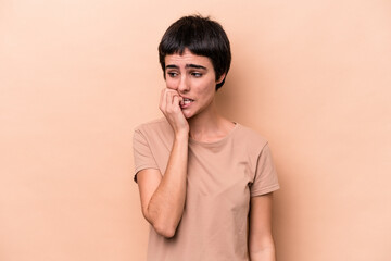Young caucasian woman isolated on beige background biting fingernails, nervous and very anxious.