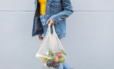 Hispanic woman with curly hair, with an ecological bag with fruit and vegetables