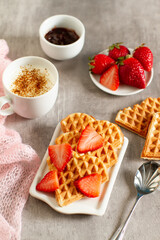 Heart-shaped waffles with strawberry jam and cappuccino