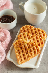 Heart-shaped waffles with strawberry jam and cappuccino