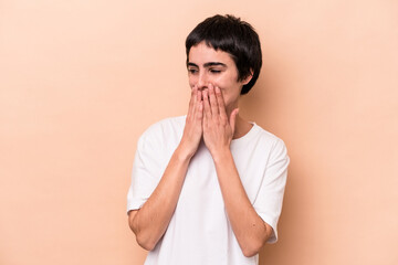 Young caucasian woman isolated on beige background laughing about something, covering mouth with hands.