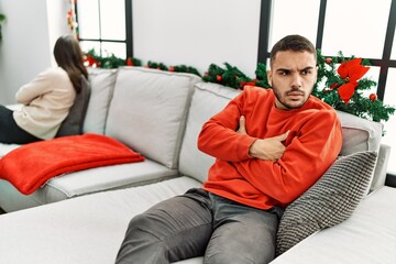 Young hispanic couple on problems with sad expression sitting on the sofa at home.