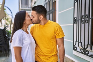 Young latin couple kissing and hugging at the city.