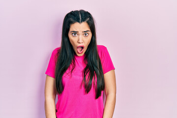 Young hispanic girl wearing casual pink t shirt afraid and shocked with surprise and amazed...