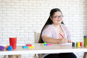portrait down syndrome girl holding pencil and writing on paper