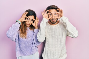 Young hispanic couple wearing casual clothes trying to open eyes with fingers, sleepy and tired for morning fatigue