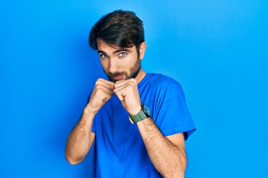 Young hispanic man wearing casual clothes ready to fight with fist defense gesture, angry and upset face, afraid of problem