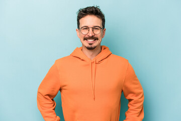 Fototapeta premium Young caucasian man isolated on blue background confident keeping hands on hips.