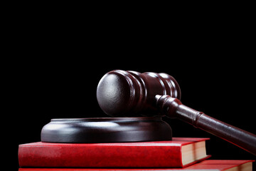 Abstract photo with wooden gavel and red book with codes on black background as symbol of of rule of law with judge's gavel, justice with judge's gavel and force of law with udge's gavel