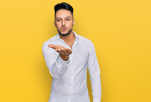 Young arab man wearing casual clothes looking at the camera blowing a kiss with hand on air being lovely and sexy. love expression.
