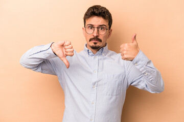 Fototapeta na wymiar Young caucasian man isolated on beige background showing thumbs up and thumbs down, difficult choose concept