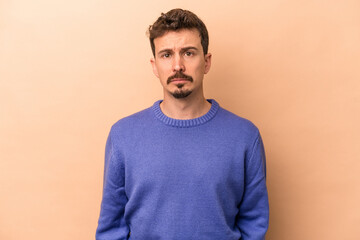 Fototapeta premium Young caucasian man isolated on beige background sad, serious face, feeling miserable and displeased.