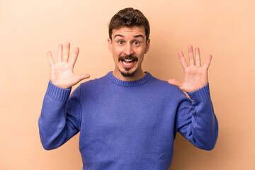 Young caucasian man isolated on beige background receiving a pleasant surprise, excited and raising hands.