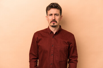 Obraz premium Young caucasian man isolated on beige background sad, serious face, feeling miserable and displeased.