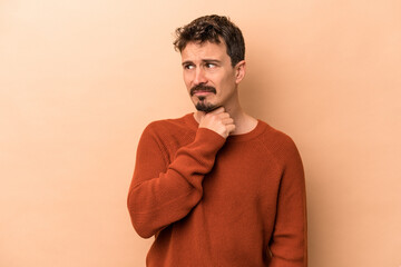 Fototapeta premium Young caucasian man isolated on beige background suffers pain in throat due a virus or infection.