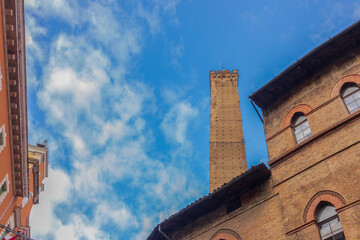 Low angle view of Asinelli tower and buildings against cloudy sky in Bologna, Italy. Copy space.