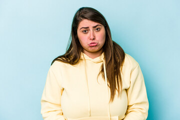 Obraz premium Young caucasian overweight woman isolated on blue background sad, serious face, feeling miserable and displeased.