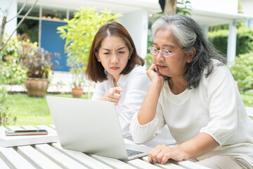 Asian daughter teaching old elderly woman use online Social media in computer laptop after retirement. Concept of Learning technology and adaptation of the elderly