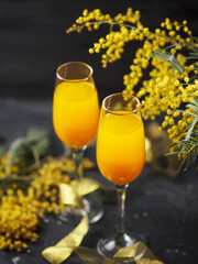 two glasses of mimosa cocktail and a bouquet of yellow mimosas