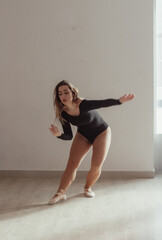 A woman standing in a dance pose in a dance studio, dressed in a dance outfit.