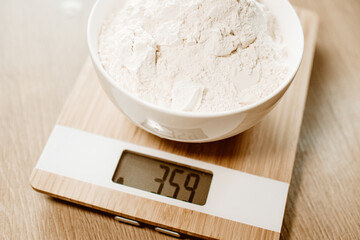 Flour in a plate stands on a kitchen scale, homemade food according to recipes.