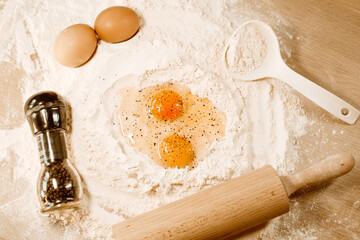 Cooking homemade dough, flour and eggs on the table. Rolling pin and pepper on eggs. Cooking at home, recipes, diet