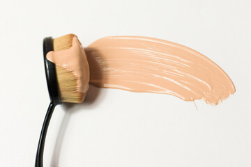 Brush for applying foundation on the face on a white background. Foundation, cosmetics flowing on...