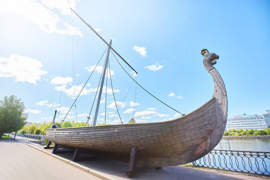 VYBORG, RUSSIA - JUNE 30, 2021: An old wooden Viking warship. General plan with a view of the city.