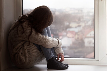 Depressed Teen sitting alone by the window. Upset Sad Teenager needs help. Teenage Problems....