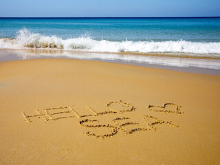Text Hello sea handwritten on wet sand by water and rising wave on a beautiful seashore Karon beach, Phuket, Thailand. Vacation by sea, travel concept. Top view