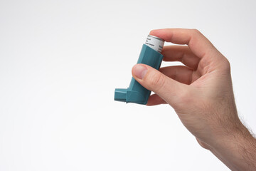 Asthma inhaler, generic, non-branded, held in hand by male hand. Close up studio shot, isolated on white background