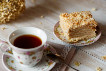 a piece of cake lies on a plate near a cup of tea