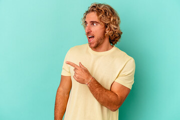 Young caucasian man isolated on blue background looks aside smiling, cheerful and pleasant.