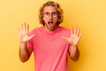 Young caucasian man isolated on yellow background receiving a pleasant surprise, excited and...