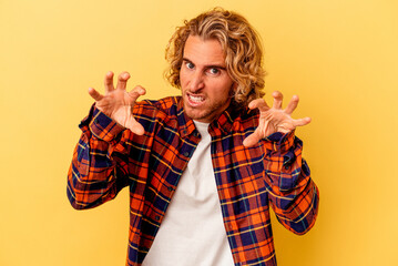 Young caucasian man isolated on yellow background upset screaming with tense hands.
