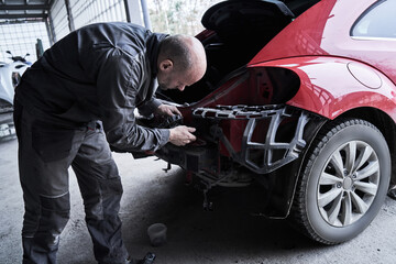 Obraz na płótnie Canvas Car service worker repairs restores car