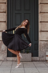 Naklejka premium A woman going into a dance pose in front of a building, dressed in a dance outfit.
