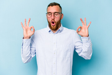 Young caucasian man isolated on blue background relaxes after hard working day, she is performing yoga.