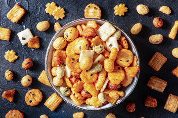 Japanese rice crackers in a bowl on a black slate background, overhead flat lay shot