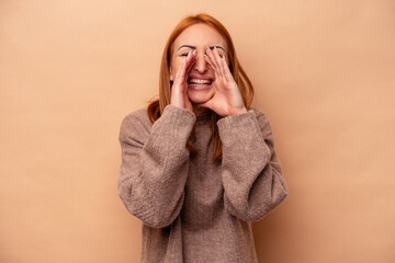 Young caucasian woman isolated on beige background saying a gossip, pointing to side reporting something.