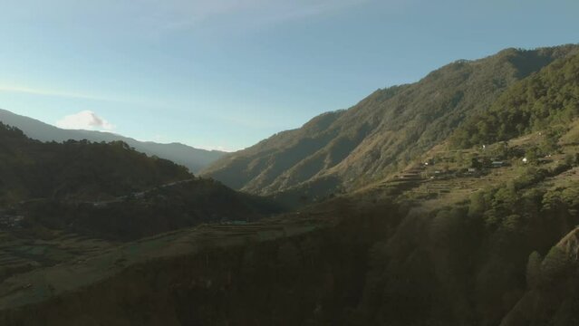 Wide reversing aerial over a mountainous valley covered in trees, farmland in Kabayan Benguet Philippines
