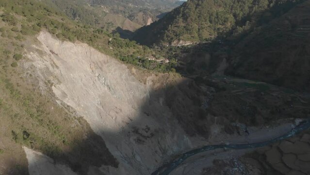 Aerial reversing and revealing a giant rock wall carved out by a river rock slide in a moutainous region of Kabayan, Benguet, Pilippines
