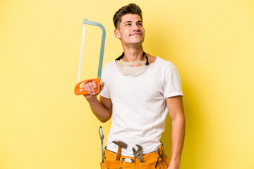 Young electrician caucasian man isolated on yellow background.dreaming of achieving goals and...