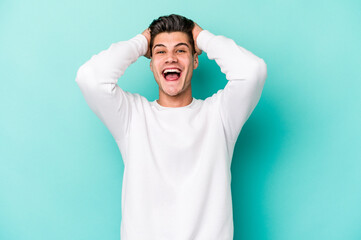 Fototapeta premium Young caucasian man isolated on blue background screaming, very excited, passionate, satisfied with something.