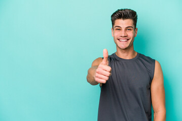 Young caucasian man isolated on blue background smiling and raising thumb up