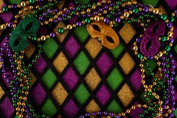 Frame of Mardi Gras Mask and colorful Mardi Gras Beads on diamond shaped background