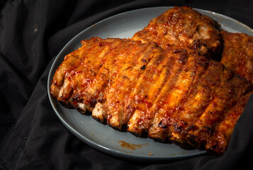 Baked pork ribs in a plate. on a dark background