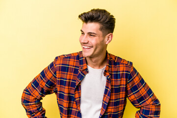 Young caucasian man isolated on yellow background confident keeping hands on hips.